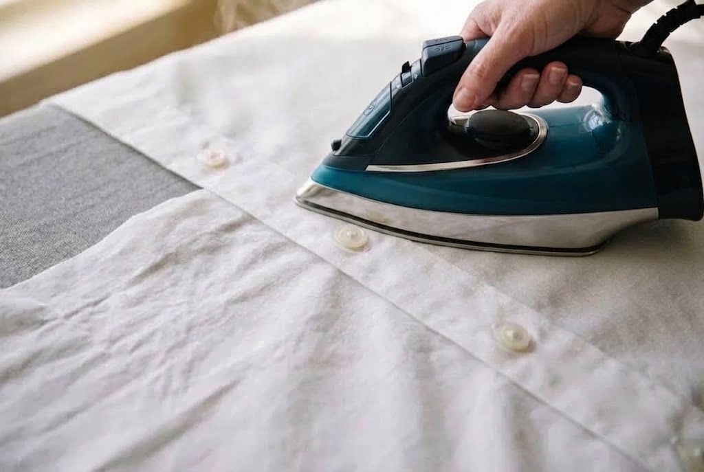 Hand-ironing around the buttons of a cotton dress shirt